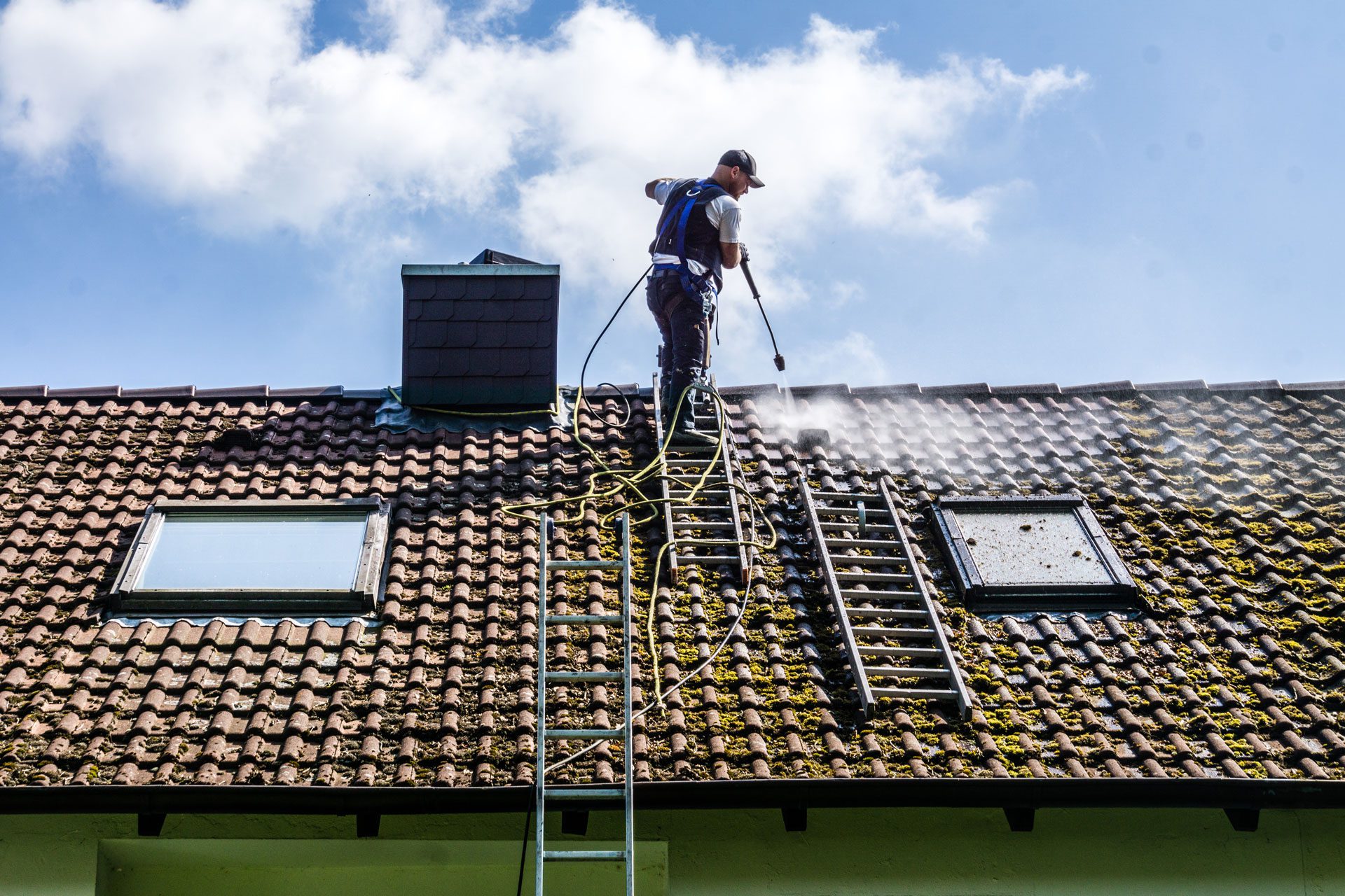 man pressure washing  a roof